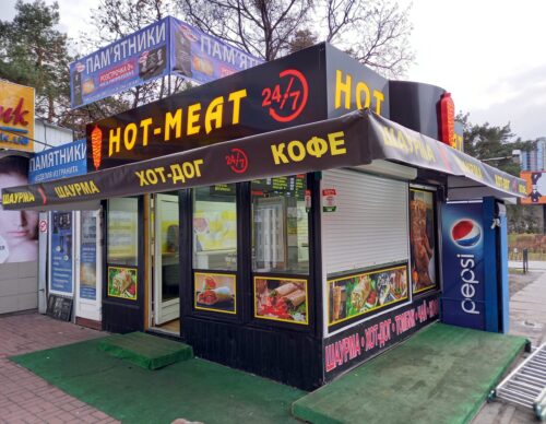 Киоск по продаже уличной еды с рекламой в виде баннеров и лайтбокса на черном фоне.